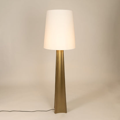 Modern floor lamp with tall metal base and wide white tapered shade glowing softly against a clean white background showcasing minimalist interior home decor lighting style.
