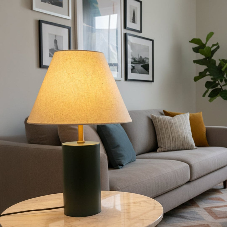 Green metal table lamp with beige fabric shade placed on side table adding warm ambient lighting to modern living room Decor.