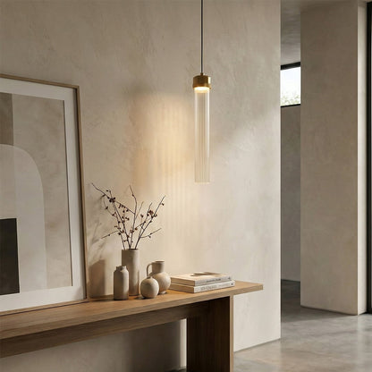 Slim gold pendant light above console table adding sophisticated warmth and modern appeal indoors.