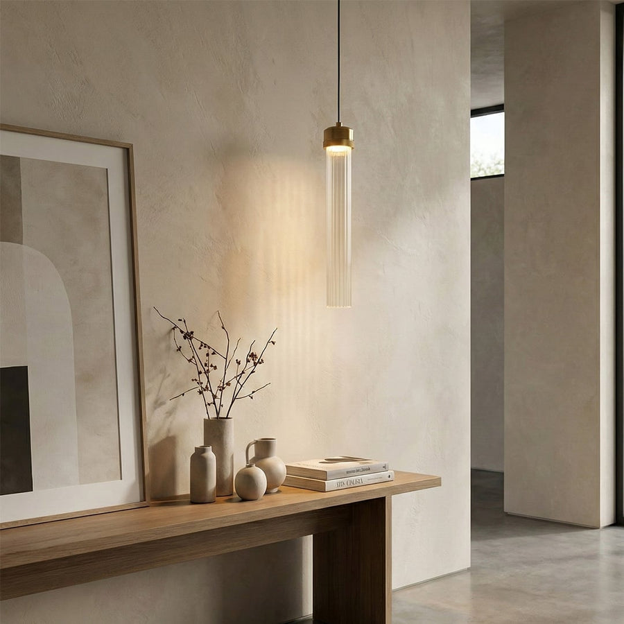 Slim gold pendant light above console table adding sophisticated warmth and modern appeal indoors.