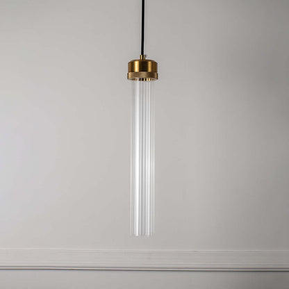 Clear glass tube pendant light with polished brass fittings crafted for elegant modern interiors.