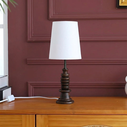 Black turned wood table lamp with white fabric shade styled on wooden console in a sophisticated interior setting.