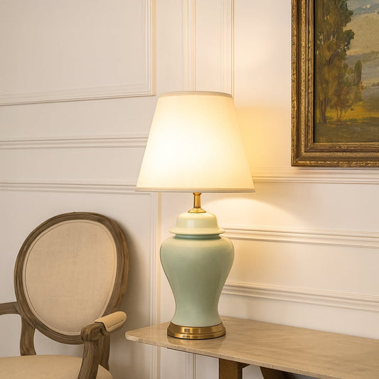 White shade jade green ceramic table lamp on wooden console table with light on and beige wall décor for classic traditional décor.
