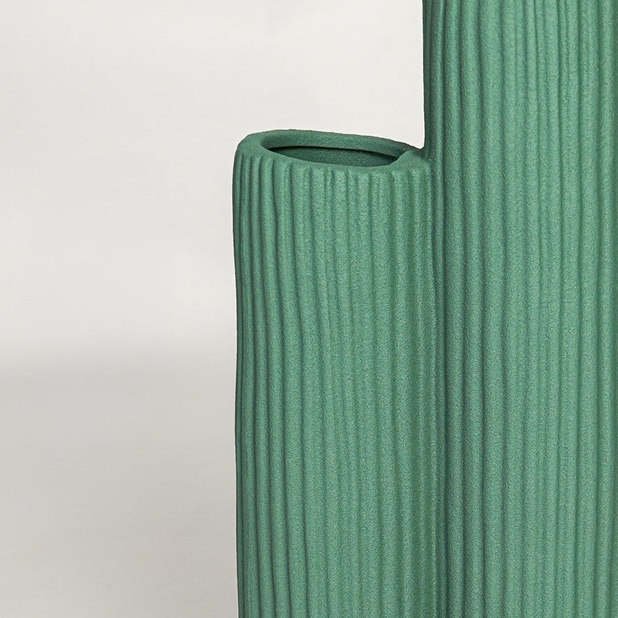 Close view of green ceramic vase showing ribbed texture matte finish and handcrafted modern sculptural design.
