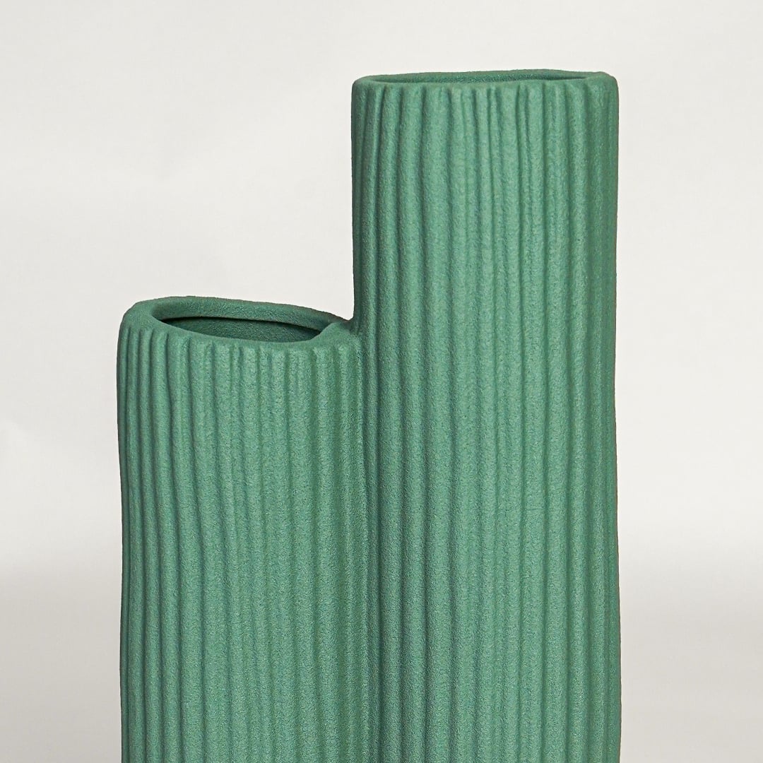 Detailed view of green ribbed ceramic vase opening showing twin tube structure and textured surface finish.