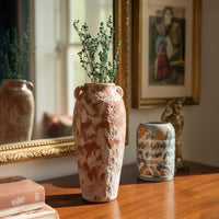 Elegant tall rustic terracotta vase and small patterned jar on console for refined classic home interior decor accents.