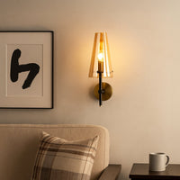 Warm wall light with amber glass shade glowing softly beside a framed artwork and sofa creating a cozy and elegant living room atmosphere with subtle ambient lighting.