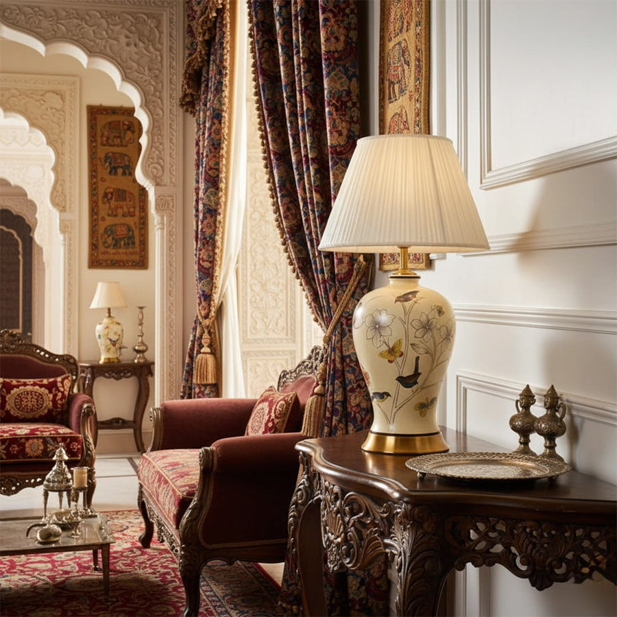 Table lamp with a floral ceramic base and pleated fabric shade placed on a carved wooden console in a royal Indian living room with ornate arches rich curtains and traditional decor.