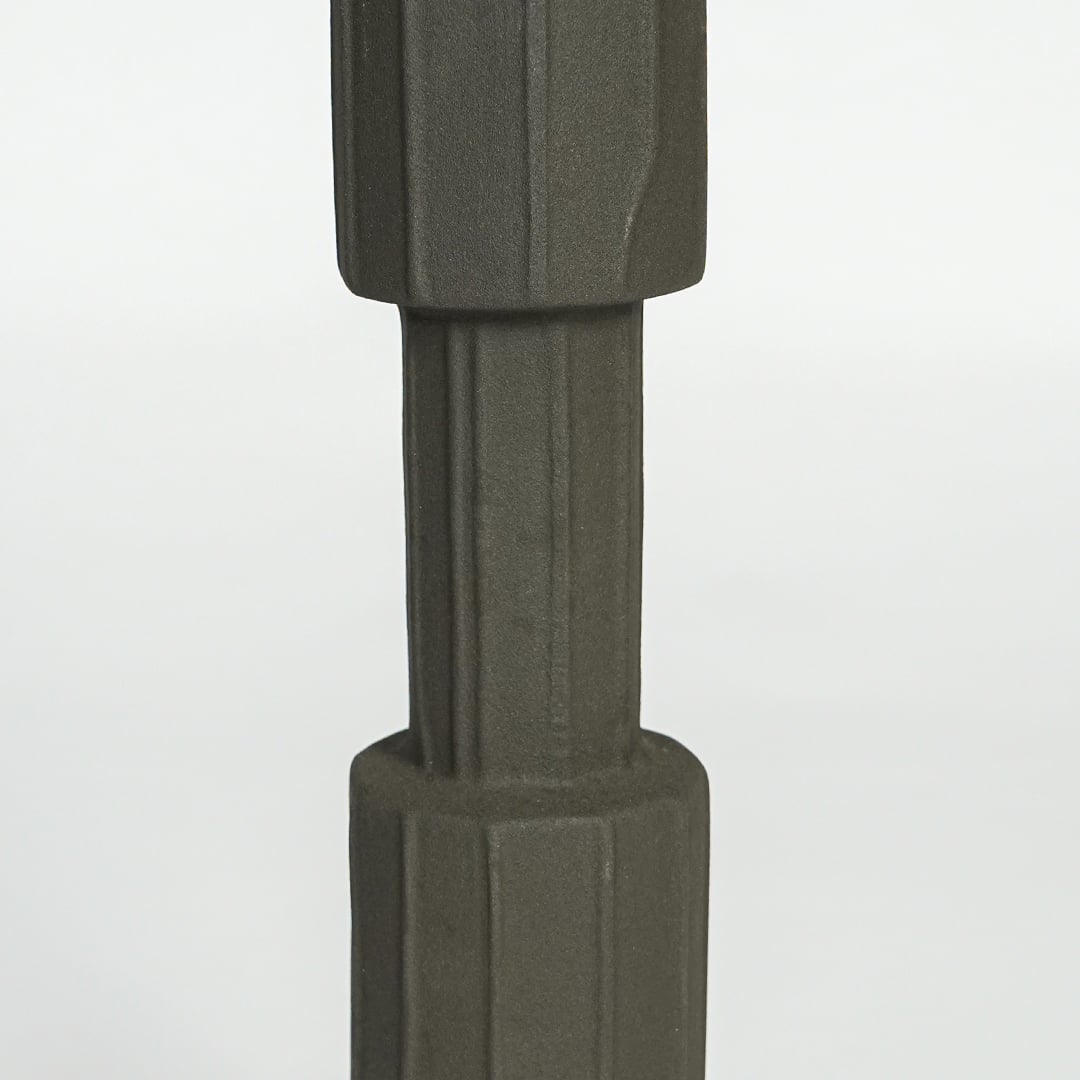 Close view of dark green metal candle holder highlighting faceted cylindrical design and matte textured finish.
