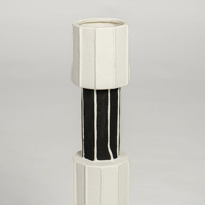 Detailed closeup of white and black metal candle holder showcasing sleek cylindrical design and glossy accents.