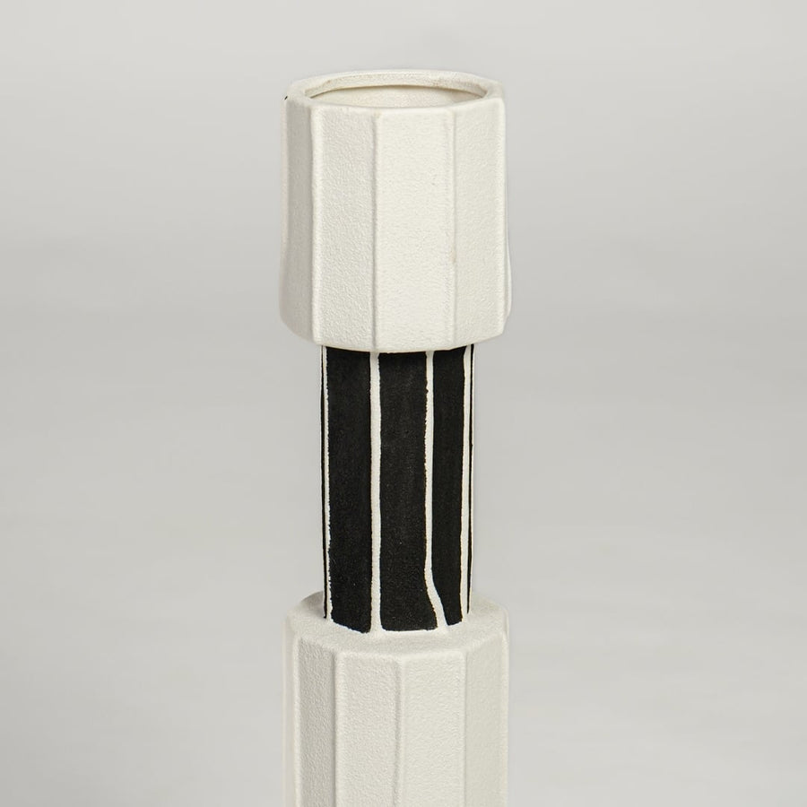Detailed closeup of white and black metal candle holder showcasing sleek cylindrical design and glossy accents.