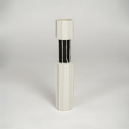 White and black metal decorative candle holder with sleek cylindrical form isolated on white background for contemporary home decor use.