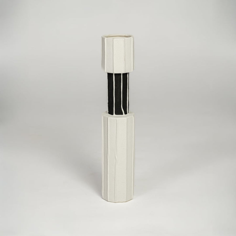 White and black metal decorative candle holder with sleek cylindrical form isolated on white background for contemporary home decor use.
