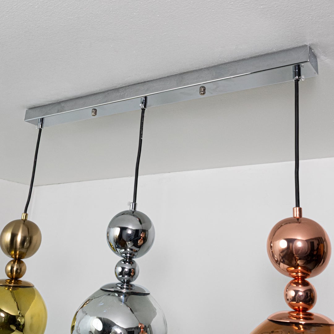 Close view of metallic pendant lights showing reflective gold silver and copper sculpted shapes highlighting their bold contemporary lighting style.