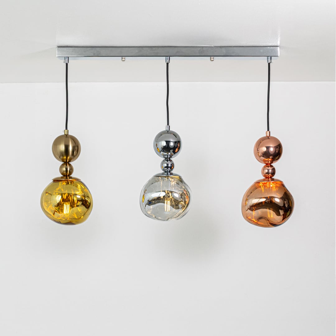 Warm glowing gold silver and copper pendant trio with sculpted reflective shades displayed on a bright white background for elegant decor inspiration.