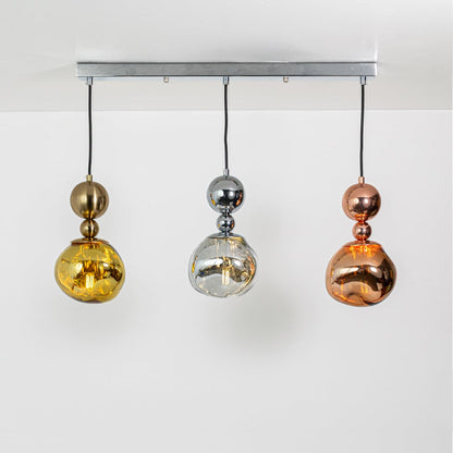 Warm glowing gold silver and copper pendant trio with sculpted reflective shades displayed on a bright white background for elegant decor inspiration.