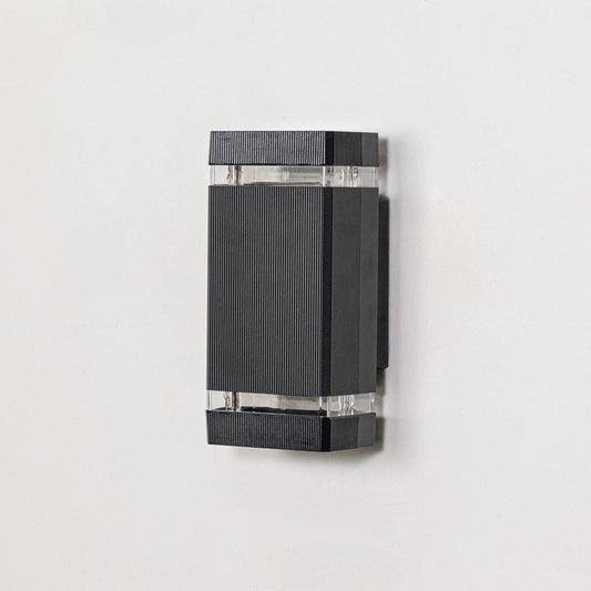 Rectangular black metal wall mounted light with ribbed finish and clear glass section displayed off on clean white background.