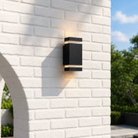 Modern black metal rectangular ribbed up down wall sconce on white brick facade for contemporary residential exterior decor.