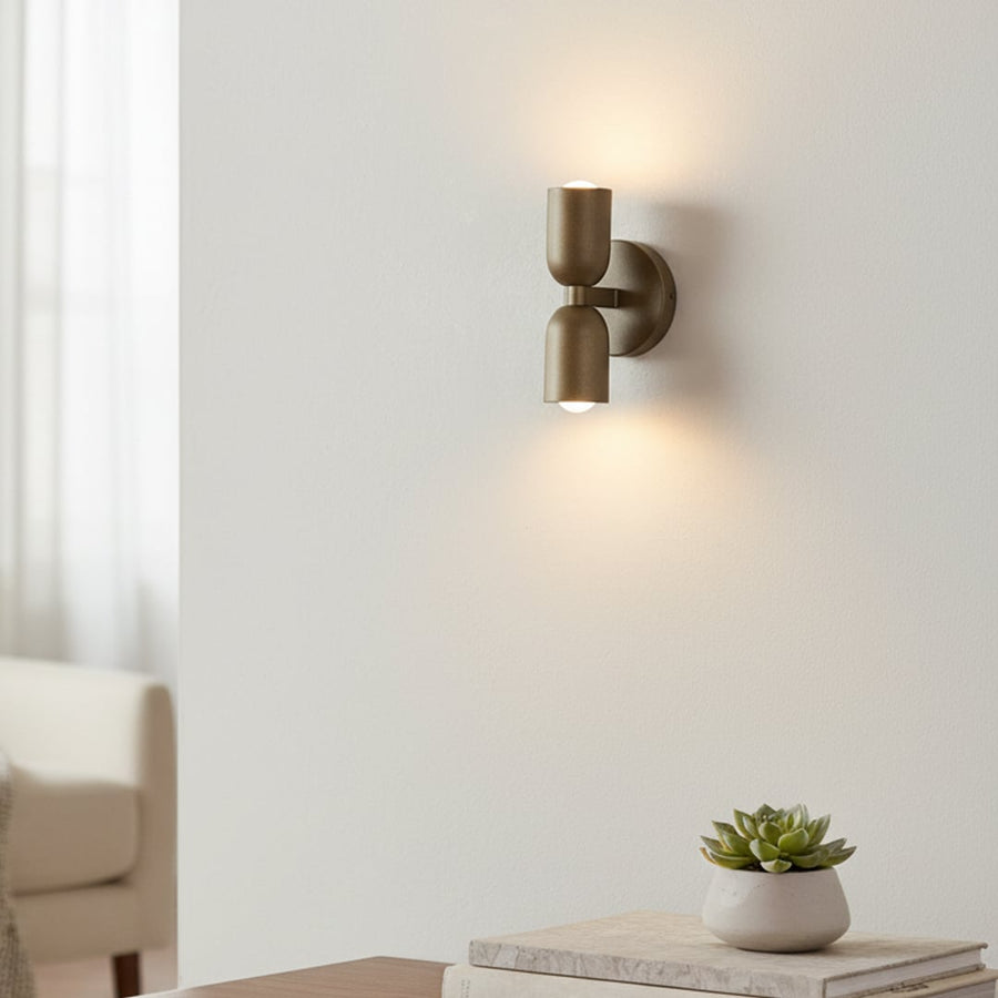 Gold double wall sconce glowing softly beside bed adding warmth and modern elegance to cozy bedroom decor.