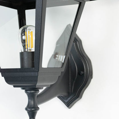 Closeup of outdoor black wall lantern showing clear glass panels and intricate detailing in a durable weather-resistant finish.