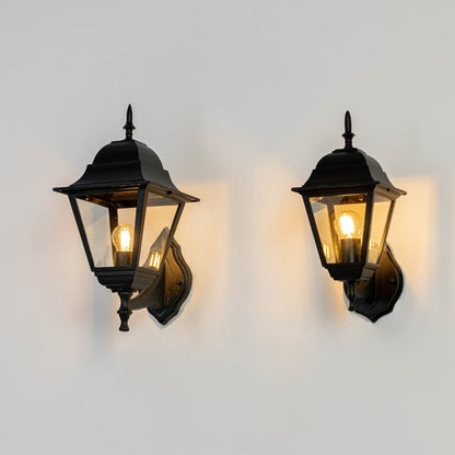 Black metal and glass outdoor wall lantern lights grouped on white background glowing warmly for porch entryway decor Light on white BG.