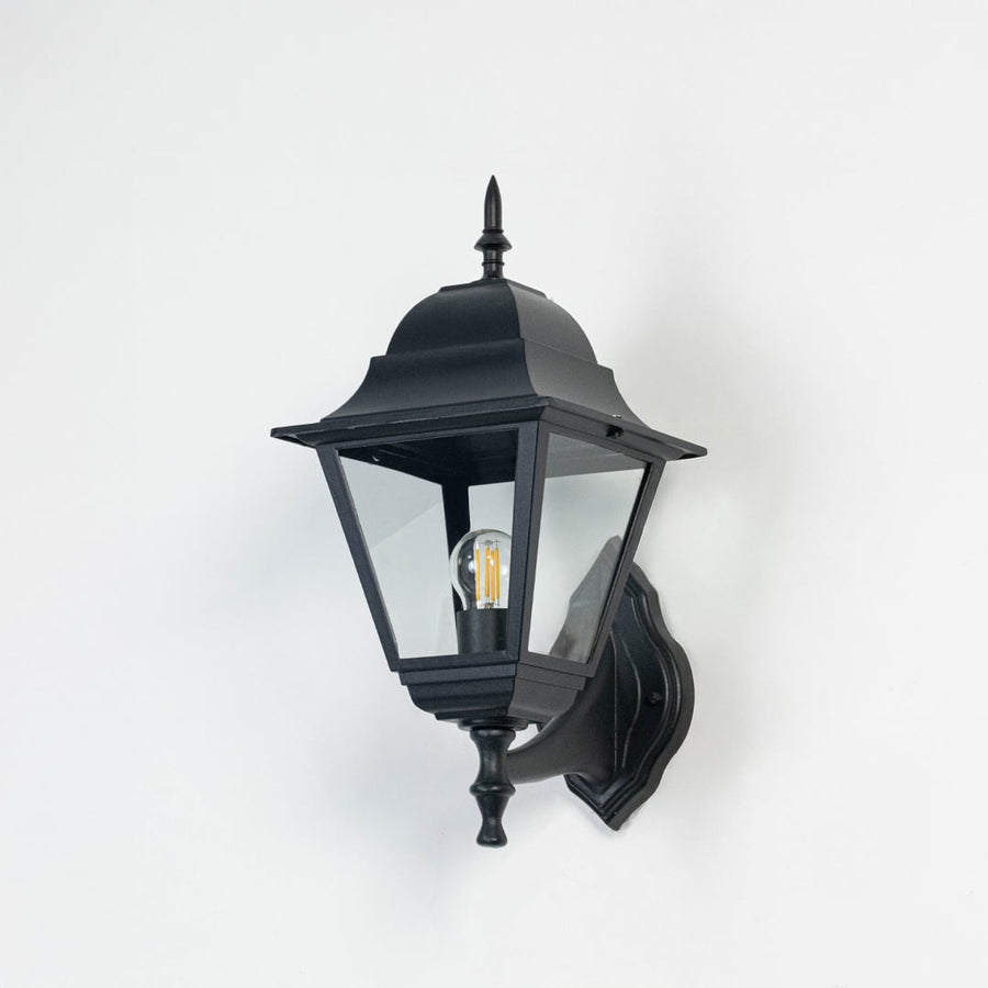 Black outdoor wall light with elegant lantern design and clear glass panels displayed on a white background with bulb turned off.