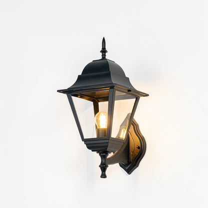 Black metal outdoor wall light on white background with clear glass shade for classic patio lighting decor.