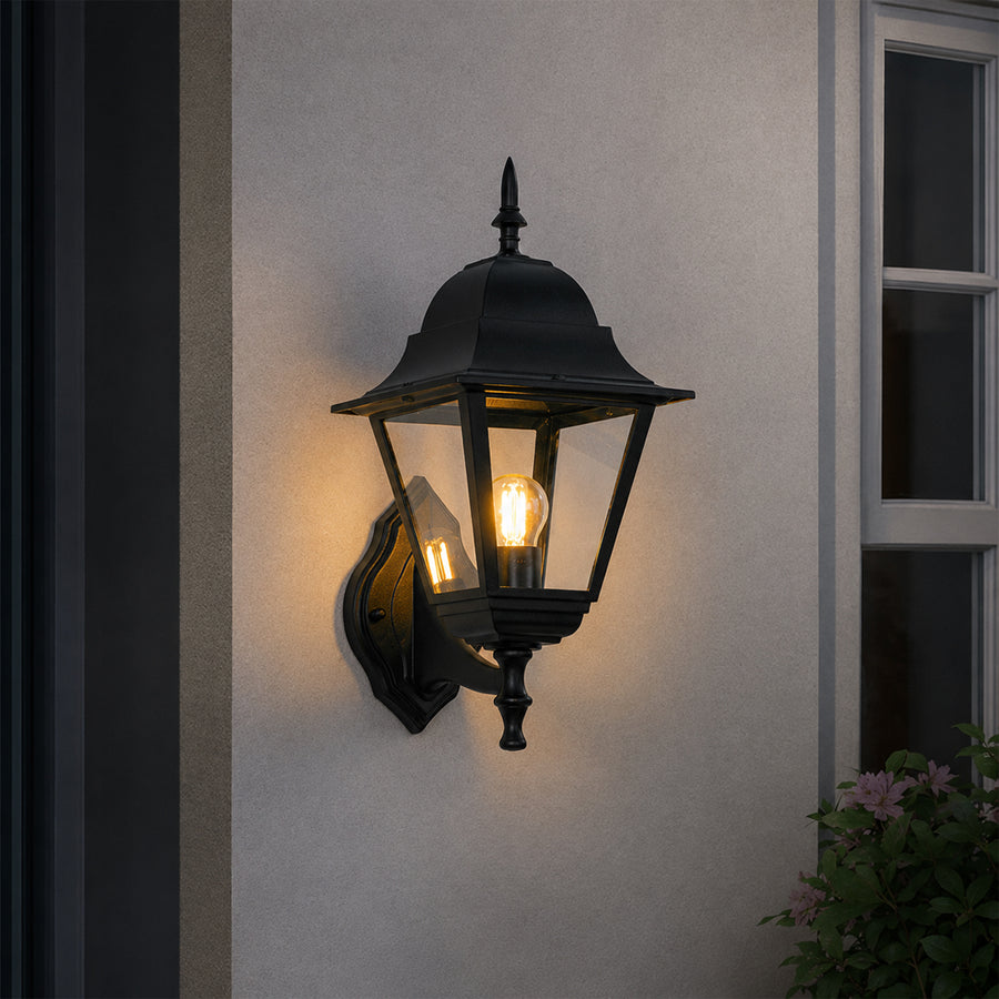 Black metal outdoor lantern wall light lifestyle image with warm glow for elegant exterior entryway decor.