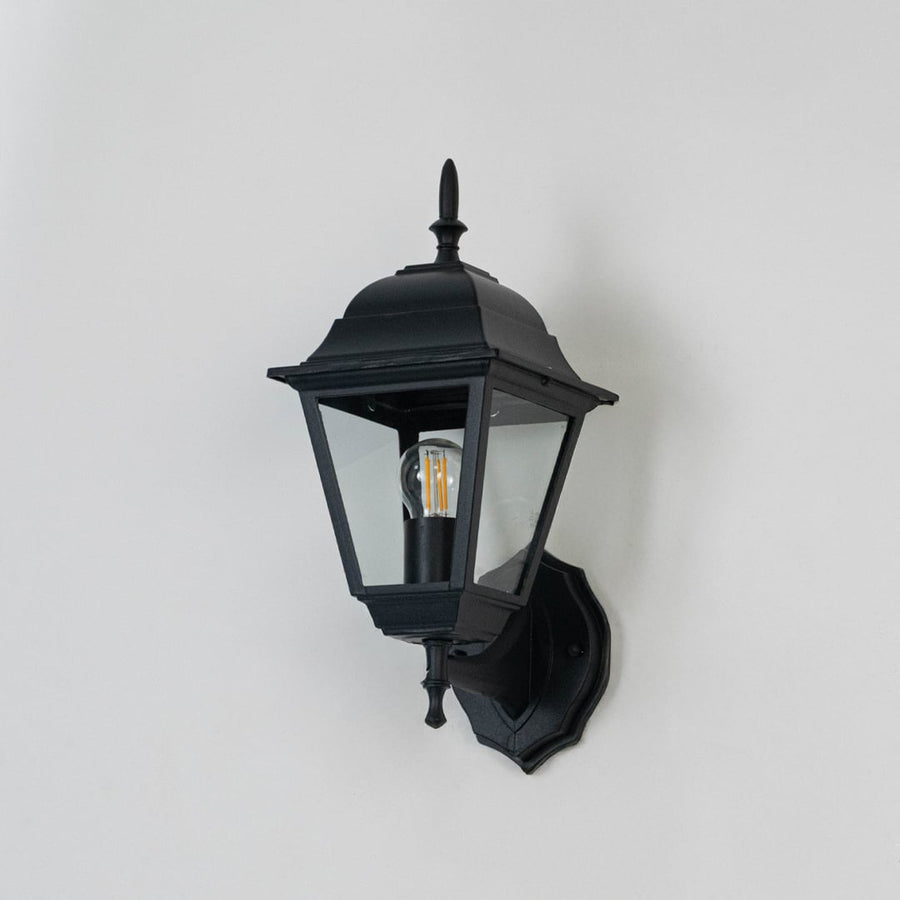 Classic black outdoor wall light shown off on white background highlighting refined lantern body and decorative finial.