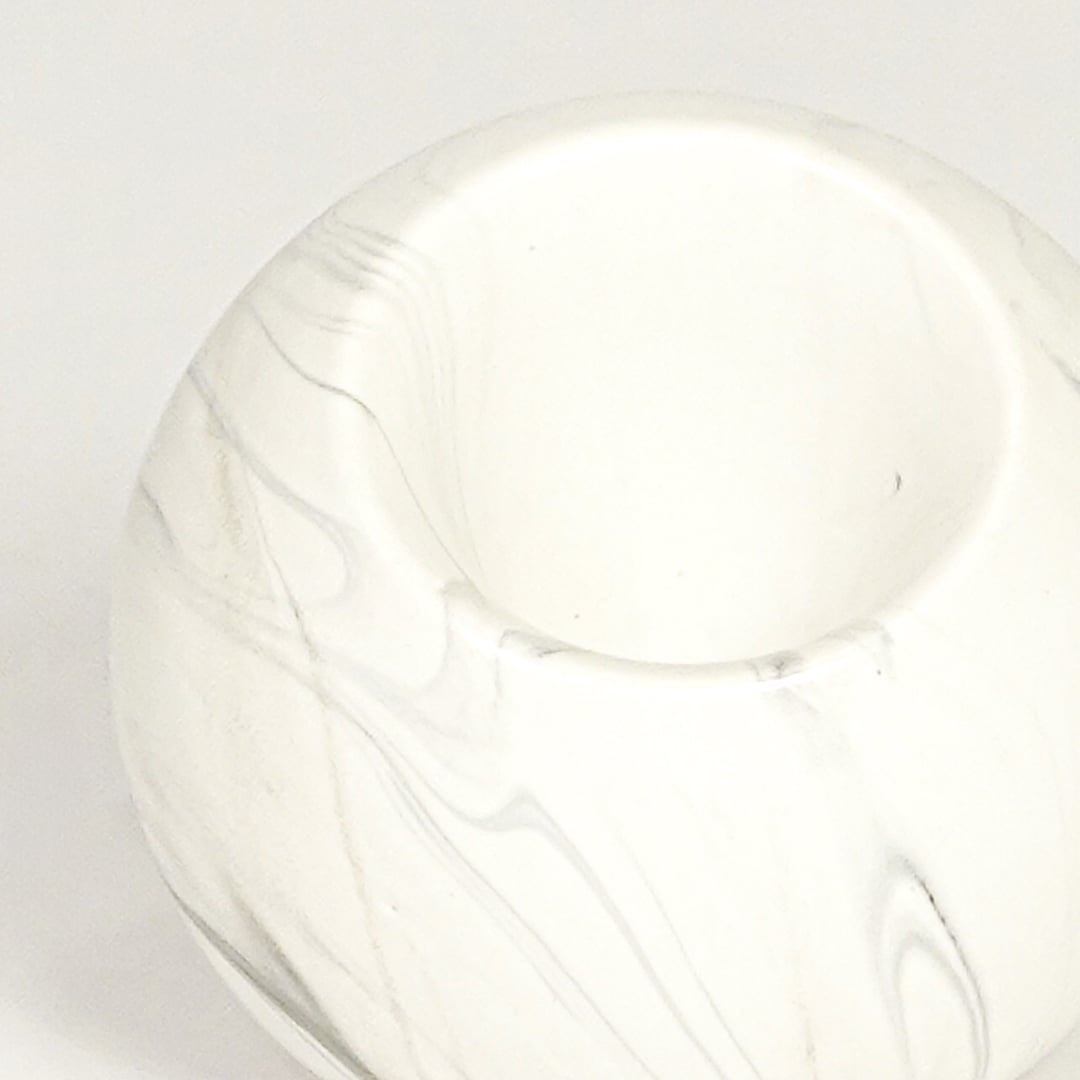 Closeup of white marble ceramic round vase showing smooth finish angled mouth and sculpted form.