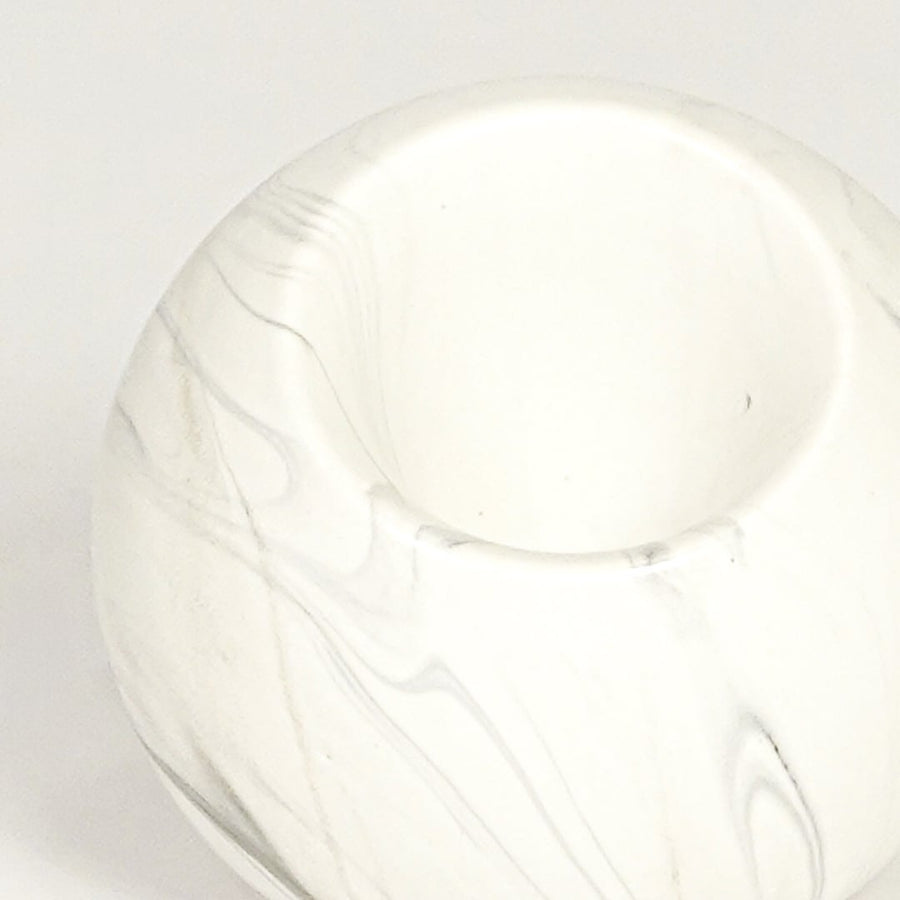 Closeup of white marble ceramic round vase showing smooth finish angled mouth and sculpted form.