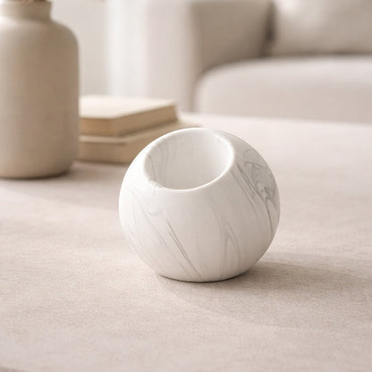 White marble finish ceramic round vase placed on tabletop in warm neutral living room styling setup.