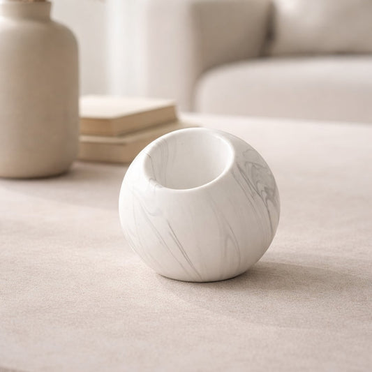 White marble finish ceramic round vase placed on tabletop in warm neutral living room styling setup.