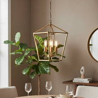 Gold metal pendant light with four clear bulbs hanging above a modern dining table creating a warm elegant and inviting interior atmosphere.