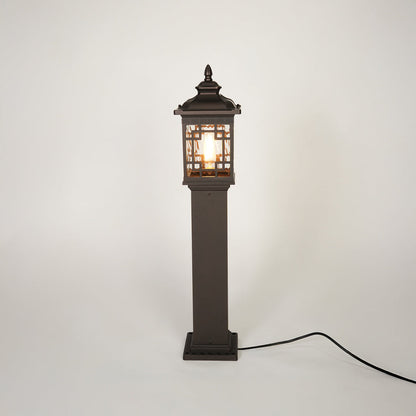 Vintage style outdoor bollard light with black metal frame and clear glass panels on neutral background perfect for garden or driveway lighting.