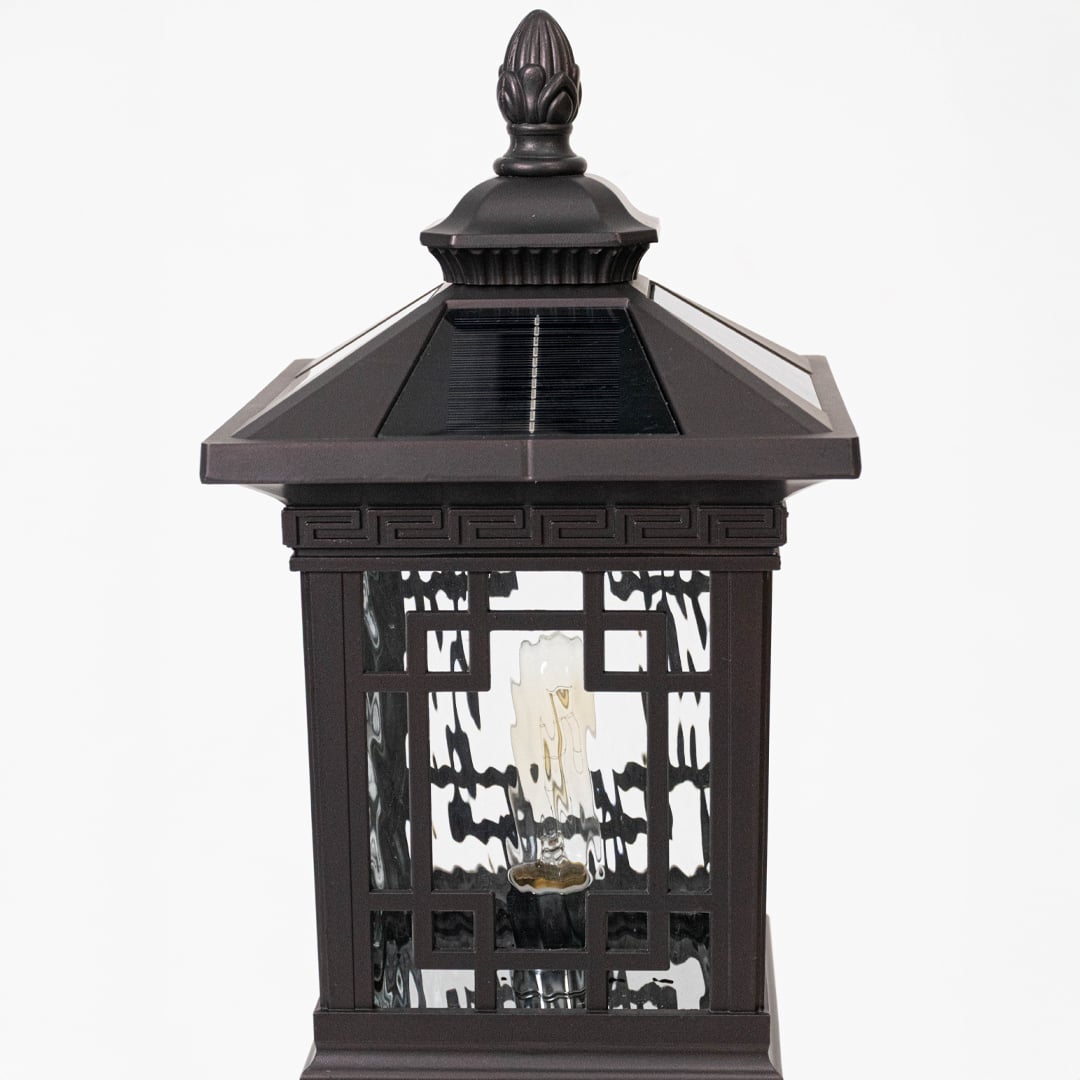 Closeup of solar outdoor lantern highlighting black metal cage design integrated solar panel and decorative exterior lighting style.