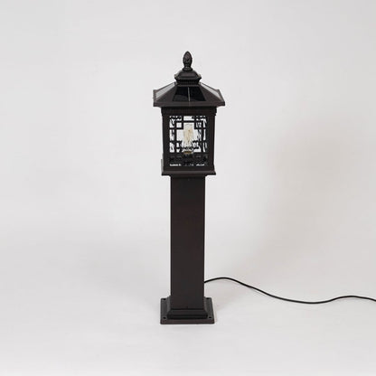 Black metal pillar lamp post with ornate design and glass panels displayed off on simple white background.