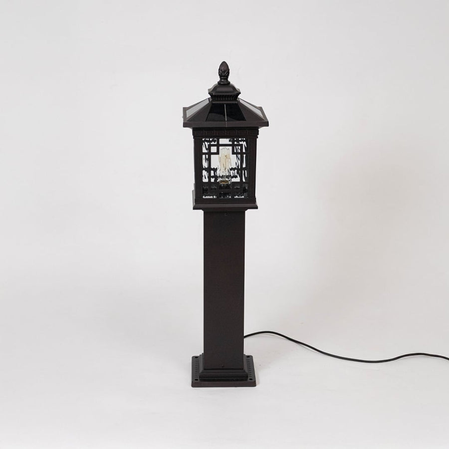Black metal pillar lamp post with ornate design and glass panels displayed off on simple white background.