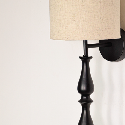 Lamp styled wall light closeup highlighting smooth black metal profile with textured fabric shade showcasing premium craftsmanship and elegant vertical design.