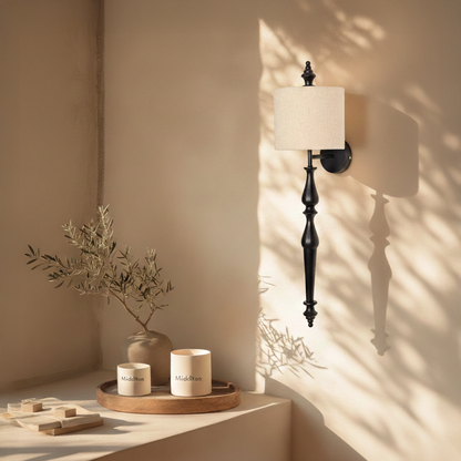 Lamp styled wall light glowing on beige wall above wooden console with black metal stem and fabric shade creating warm modern luxury Decor.