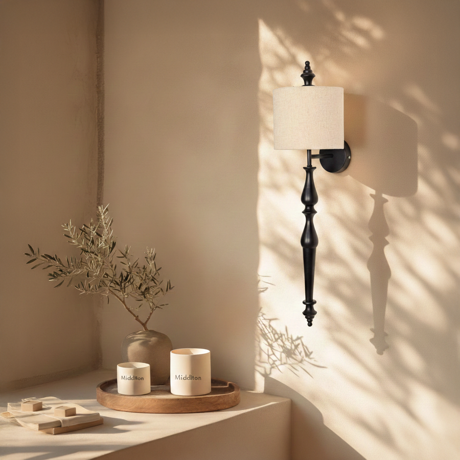 Lamp styled wall light glowing on beige wall above wooden console with black metal stem and fabric shade creating warm modern luxury Decor.