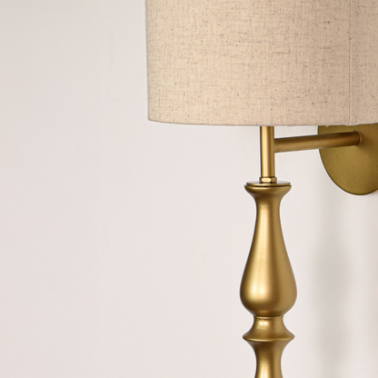Lamp styled wall light closeup highlighting smooth gold metal profile with textured fabric shade showcasing premium craftsmanship and elegant vertical form.
