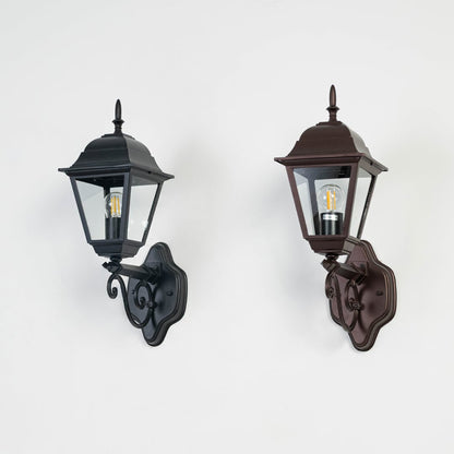 Black metal exterior wall lantern switched off on white background showcasing classic shape and decorative mounting arm.