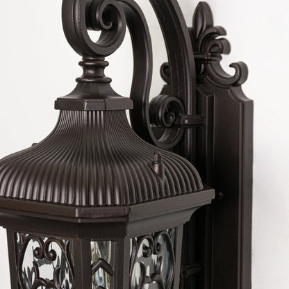 Detailed closeup image of ornate scrollwork on a traditional bronze metal wall light fixture for luxury home styling.