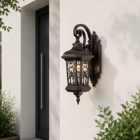 Classic black outdoor wall lantern with ornate metal detailing and clear glass panels installed beside a contemporary front door.
