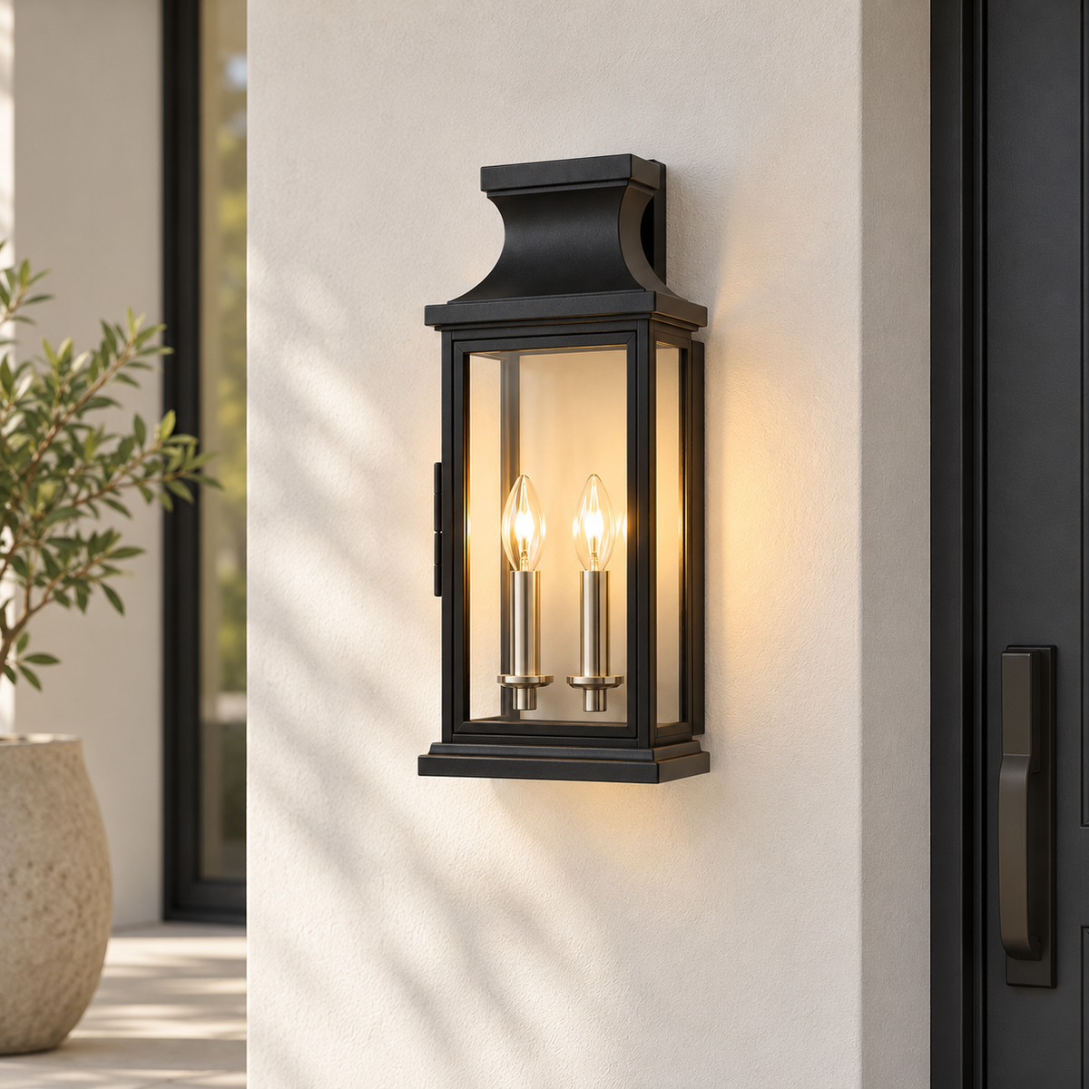 A black outdoor wall sconce with two candle-style bulbs glowing inside, mounted on a light beige stucco wall next to a dark door.