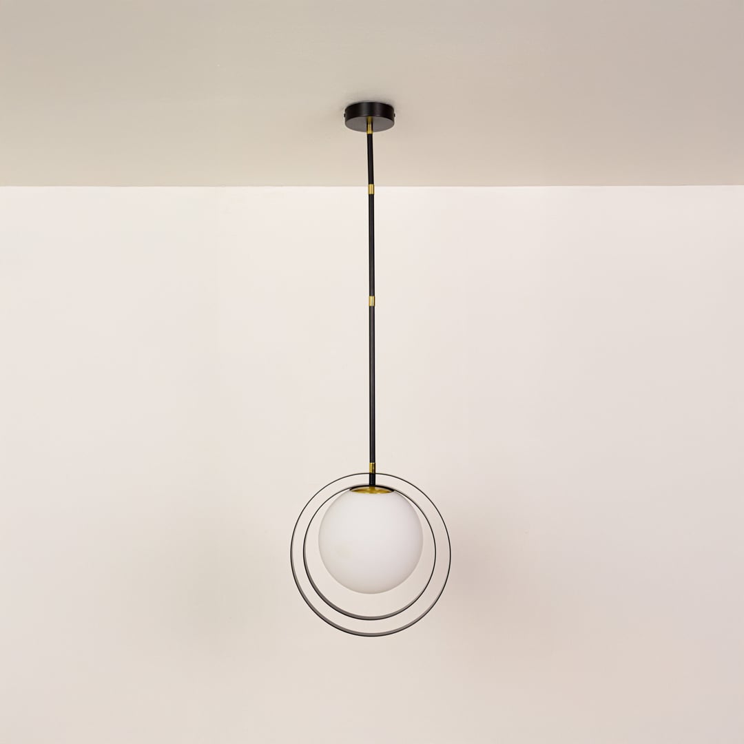 Black metal pendant light with white globe shown on a bright white background with lights off for a minimal modern look.