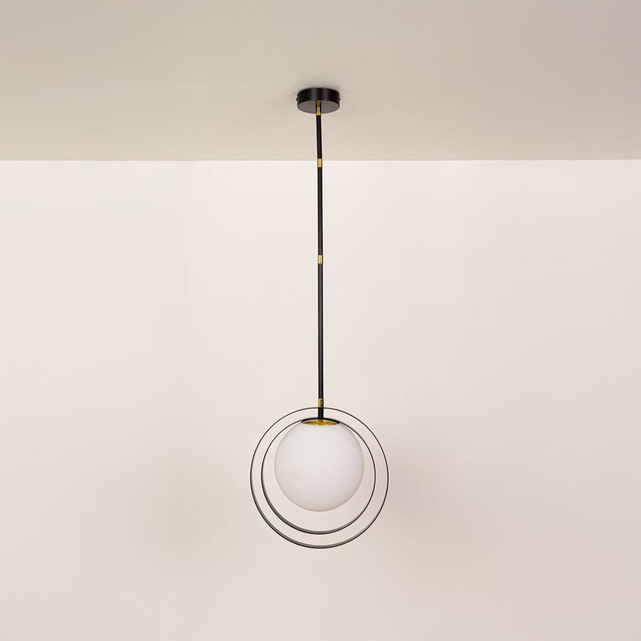 Black metal pendant light with white globe shown on a bright white background with lights off for a minimal modern look.