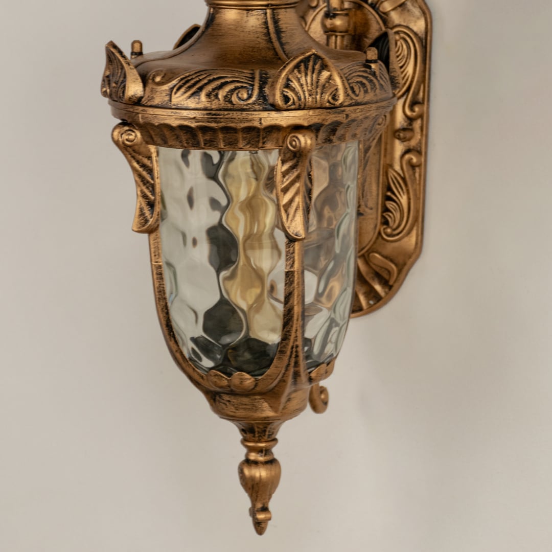 A closeup of the antique outdoor lantern highlighting the hammered glass warm inner glow and decorative carved details that create a luxurious classic lighting style.