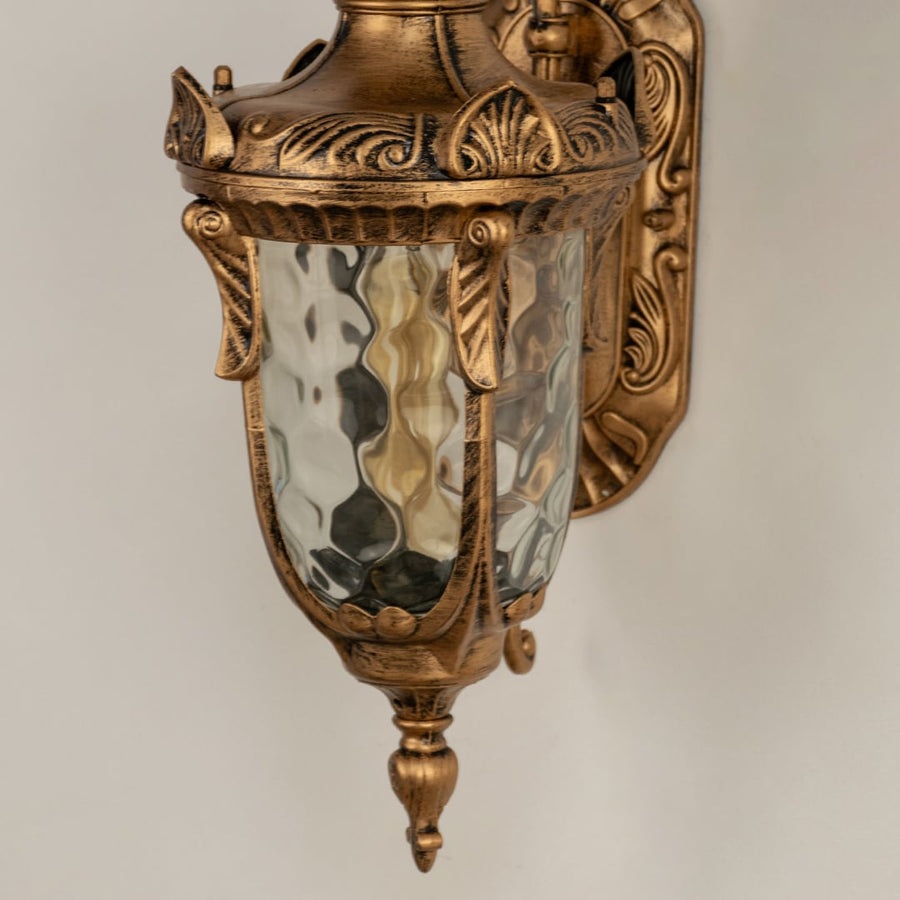 A closeup of the antique outdoor lantern highlighting the hammered glass warm inner glow and decorative carved details that create a luxurious classic lighting style.